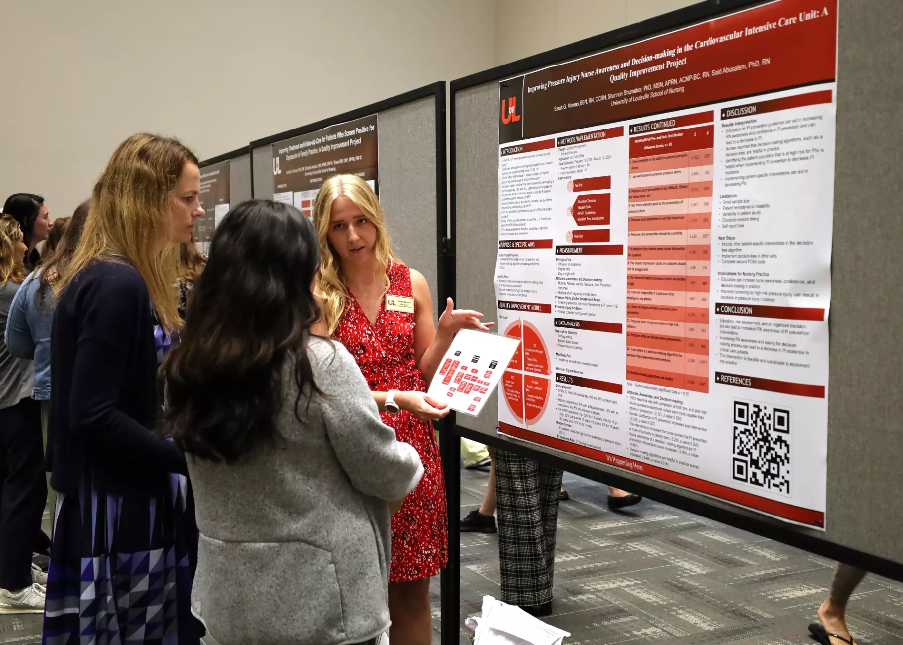 DNP student engaged in poster presentation conversation with two guests.
