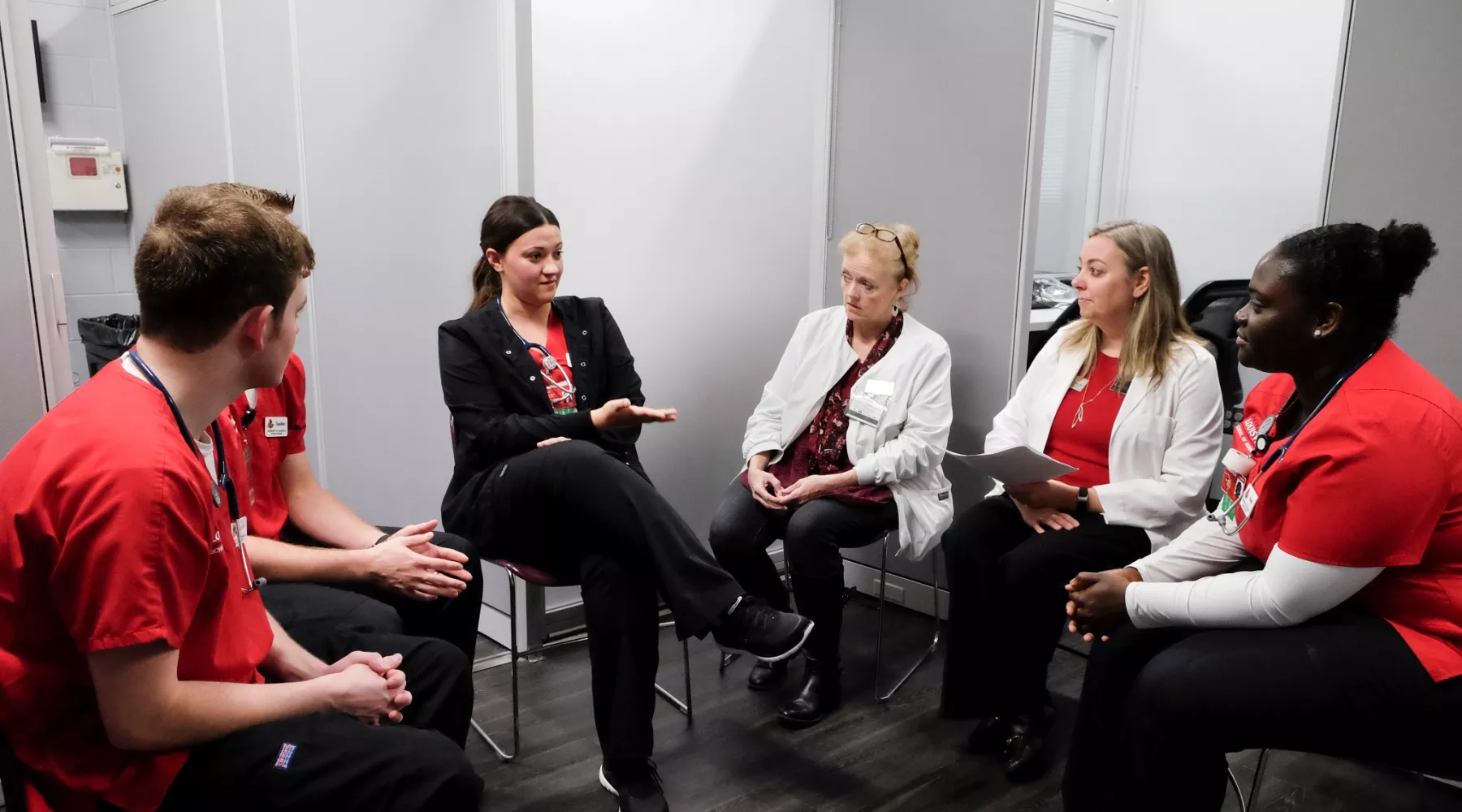Simulation faculty and nursing students seated in a semi circle to discuss the results of a simulation.