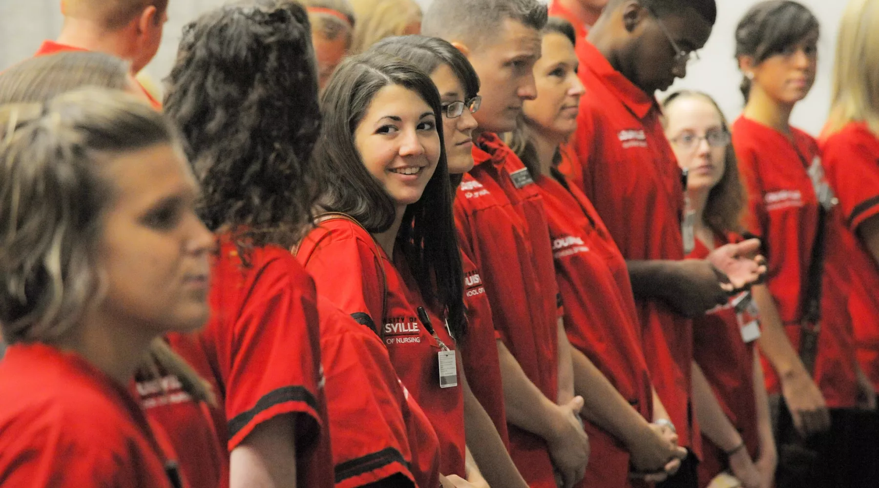 Nursing students standing together in an auditorium during a ceremony.