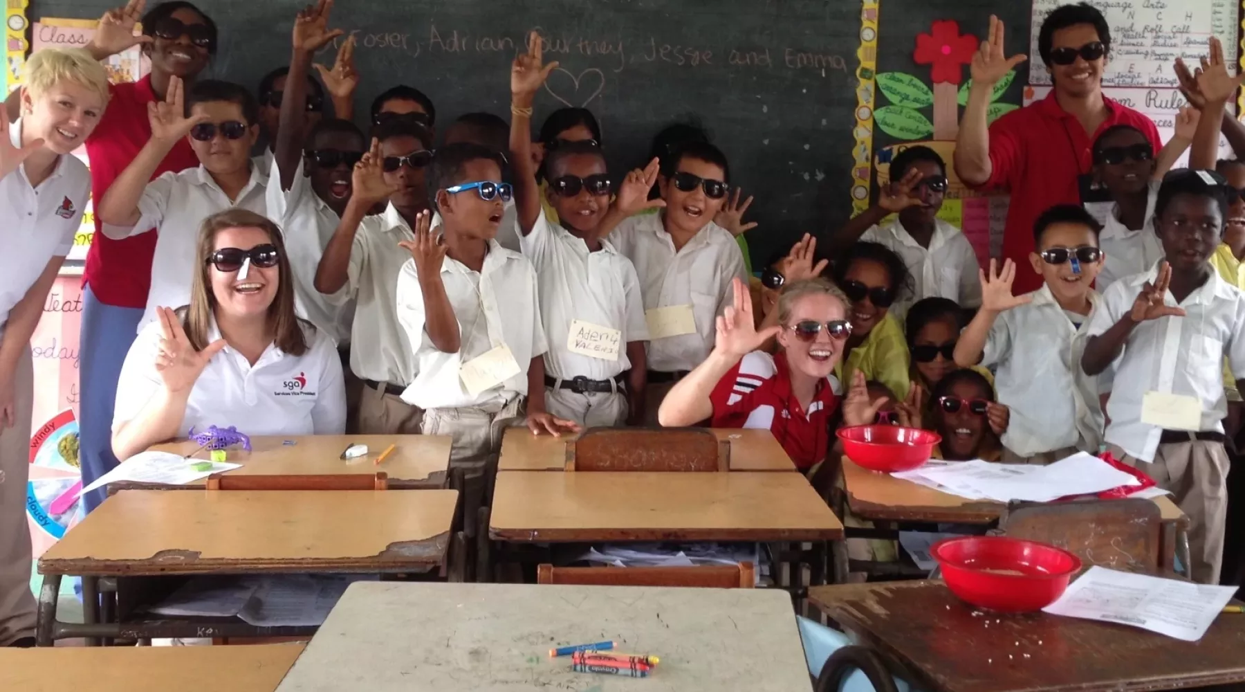Nursing students and faculty posing with elementary-aged students in an elementary classroom.