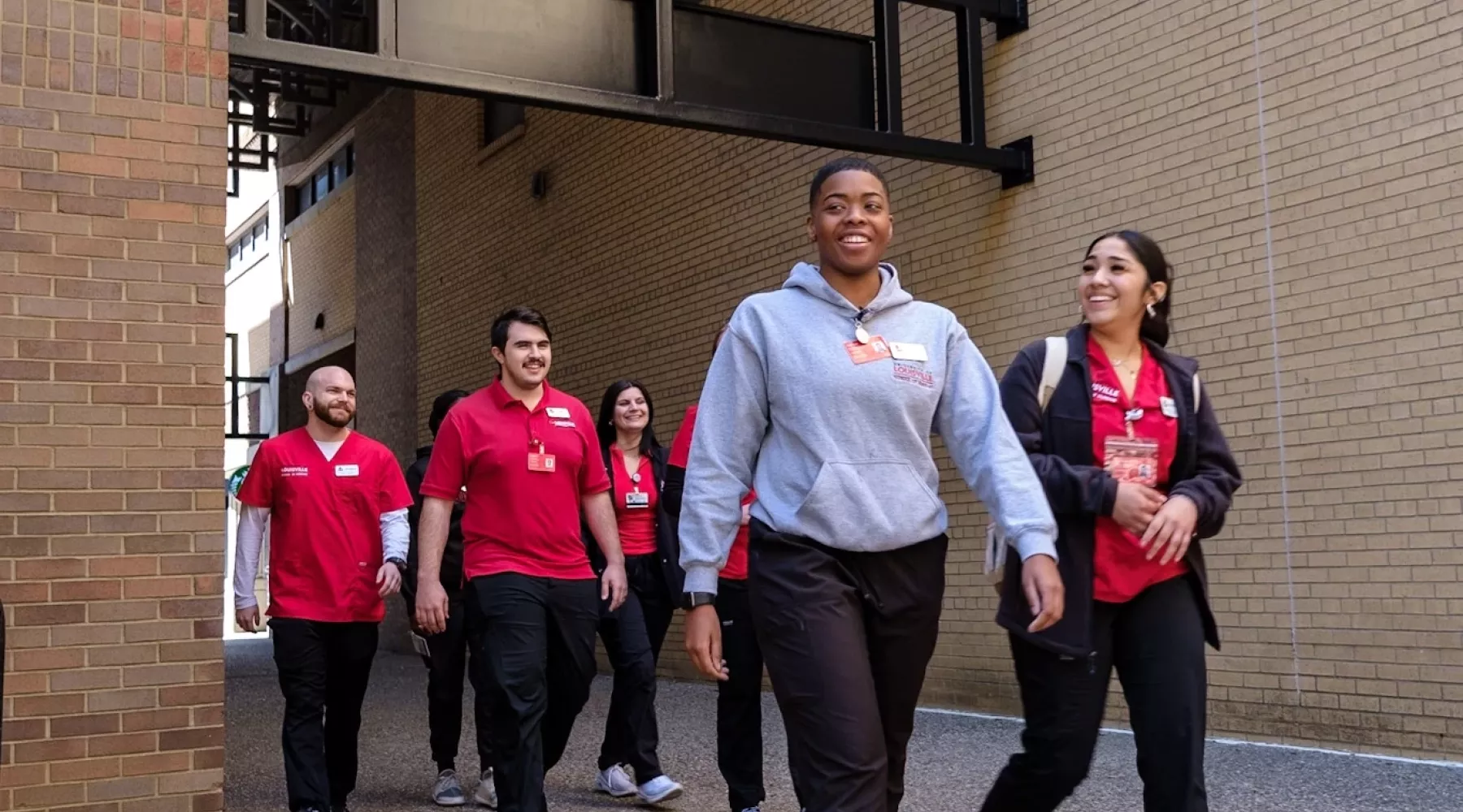 Nursing Students walking under UofL archway next to the School of Nursing.