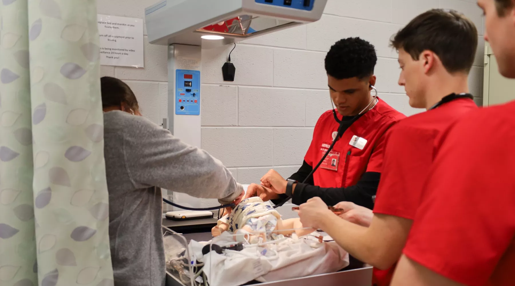 BSN students performing a clinical simulation with infant manikin.