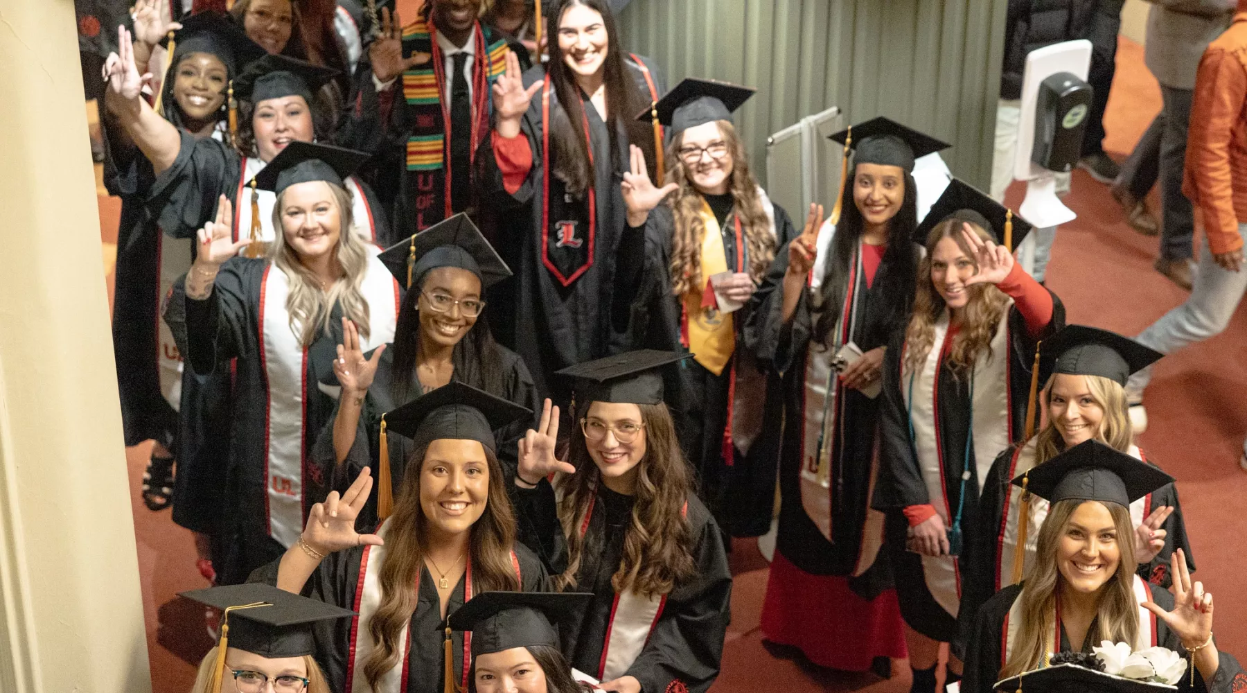 2024 winter Convocation ceremony for UofL School of Nursing graduates at the Brown theater. Graduates outside the theater stand together at the beginning of the ceremony. They give L's up to the camera and pose.
