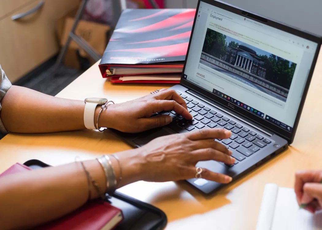 Employee typing on laptop in a UofL office