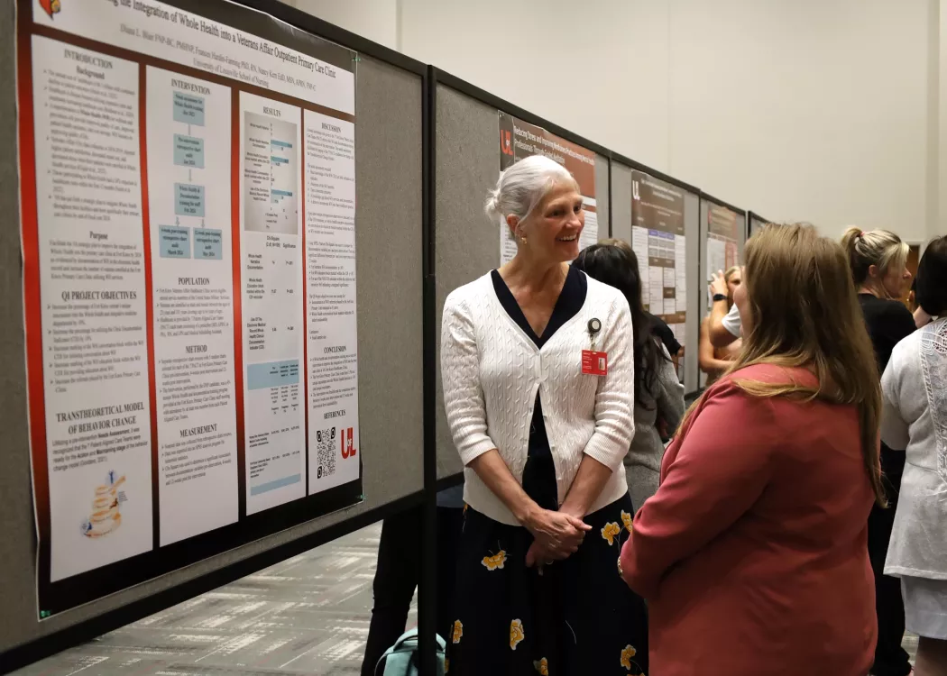 DNP student engaged in poster presentation conversation with DNP faculty member Dr. Courtney Albers.