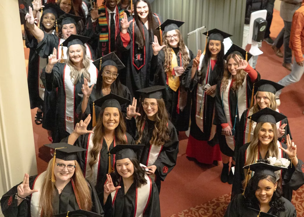 2024 winter Convocation ceremony for UofL School of Nursing graduates at the Brown theater. Graduates outside the theater stand together at the beginning of the ceremony. They give L's up to the camera and pose.