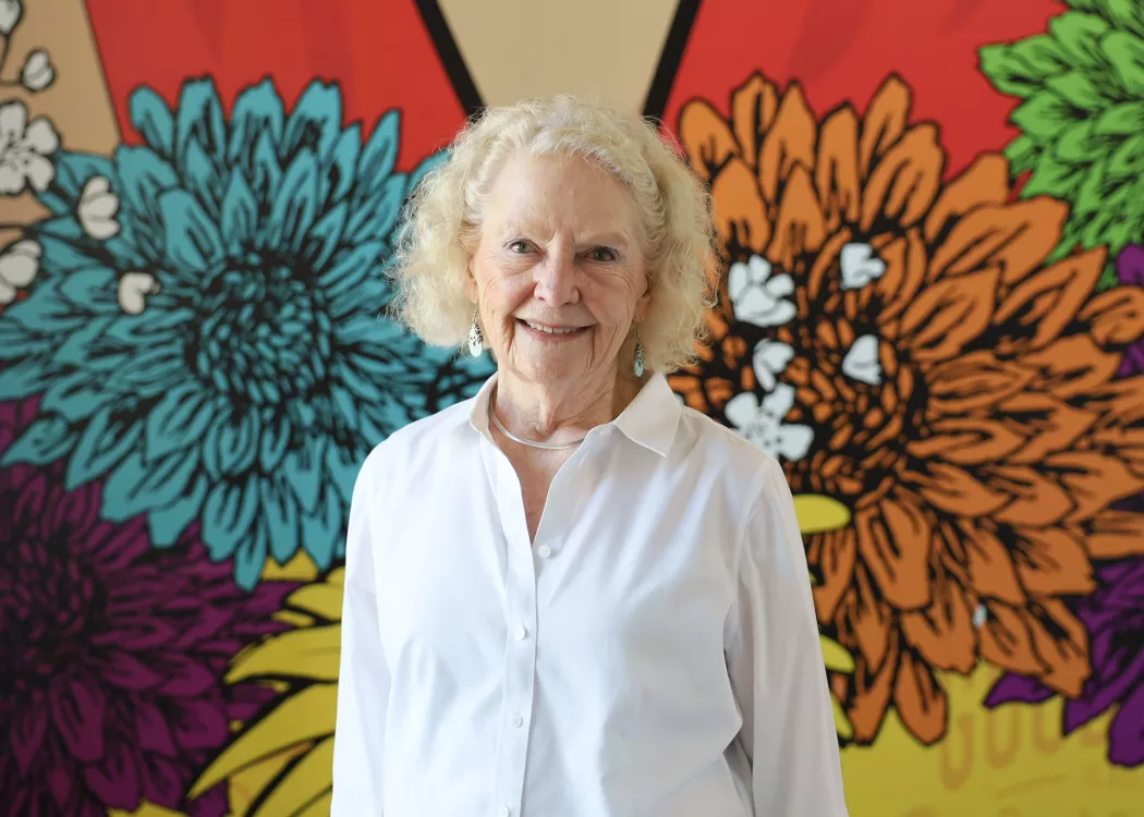 University of Louisville School of Nursing alumnus, Patricia Howard, standing in front of a multicolored, floral mural.