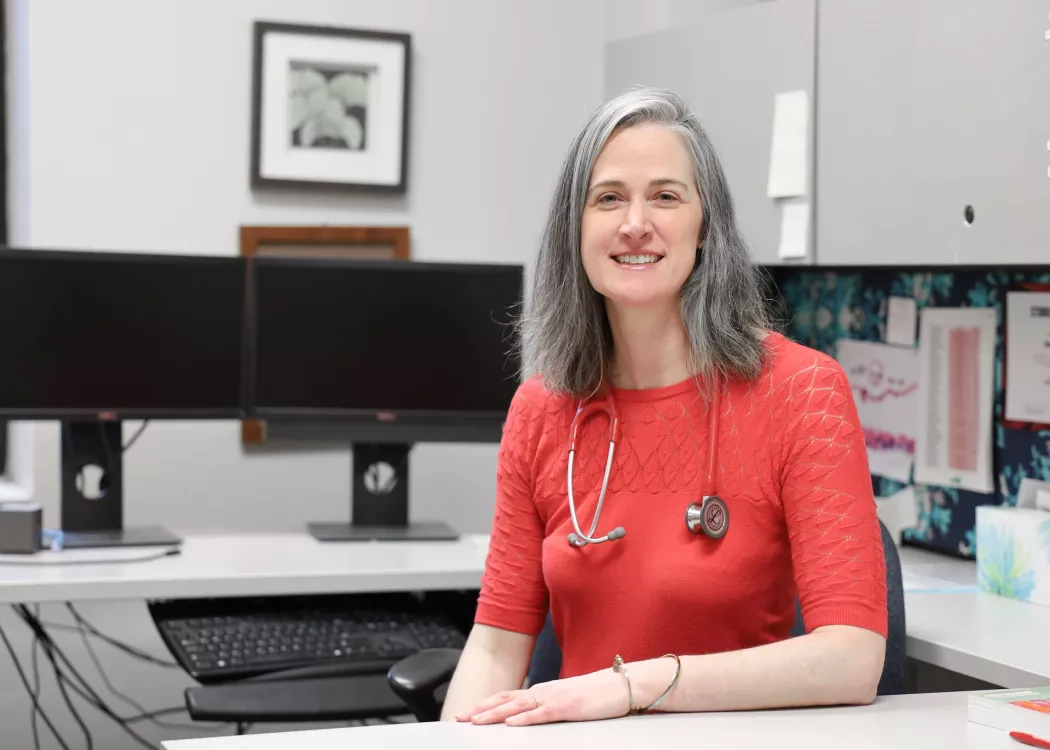 University of Louisville School of Nursing Professor and Kentucky Health Racing Services Center practitioner, Sarah Carter in the School of Nursing. Sarah sits in her office with a stethoscope around her neck.