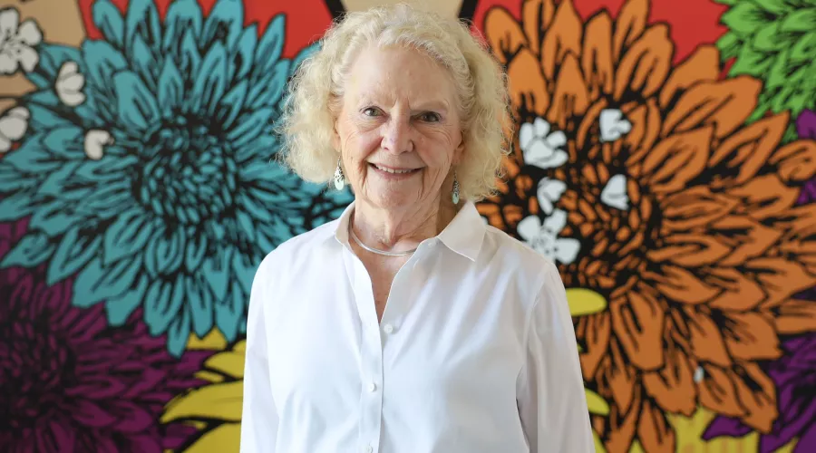 University of Louisville School of Nursing alumnus, Patricia Howard, standing in front of a multicolored, floral mural.