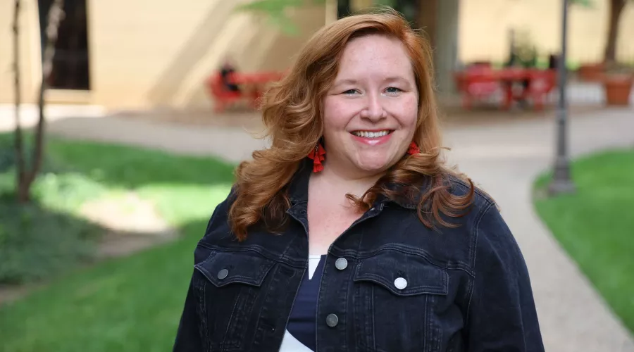 University of Louisville School of Nursing Academic advisor, Lauren McCurdy, standing outside the School of Nursing building on a sunny day, smiling at the camera.